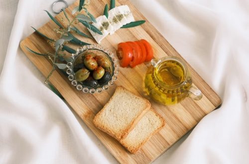 A delicious assortment of olives, cheese, tomatoes, and bread arranged on a wooden board.
