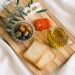 A delicious assortment of olives, cheese, tomatoes, and bread arranged on a wooden board.