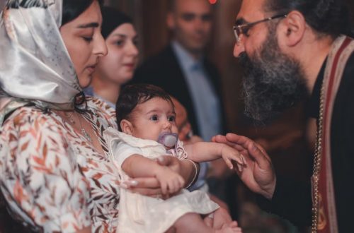 A touching moment during a baby's baptism ceremony, featuring a priest and family.